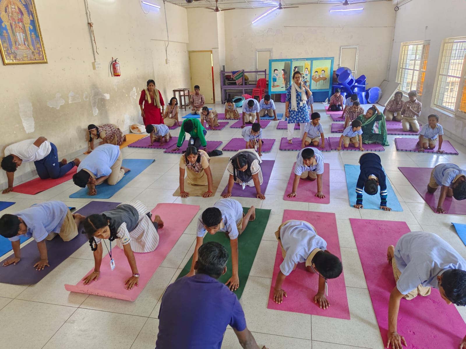 KRM Special School students and teachers practising yoga stretches on mats